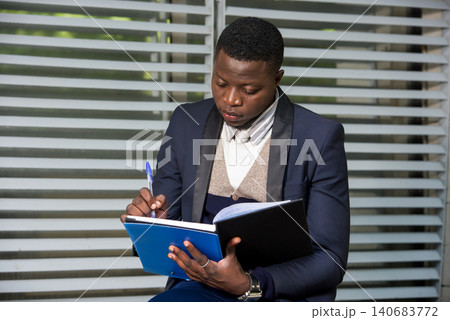 Portrait of handsome man in suit making notes on workplace outside. 140683772