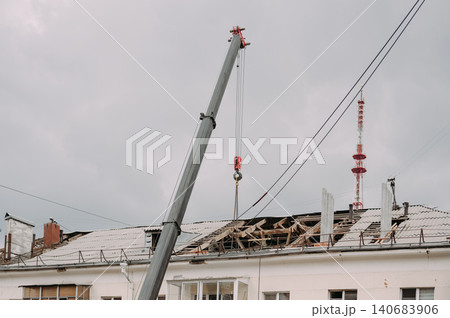 Mobile crane lifting construction materials during roof renovation of residential building Mobile crane lifting construction materials during roof renovation of residential building 140683906