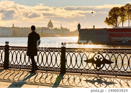 Isaac cathedral, Winter Palace, picturesque metal railings with a double-headed eagle and the crown of the Russian Empire on embankment in St. Petersburg, autumn sunset, incredible sun glare, Russia Isaac cathedral, Winter Palace, picturesque metal railings with a double-headed eagle and the crown of the Russian Empire on embankment in St. Petersburg, autumn sunset, incredible sun glare, Russia 140683924