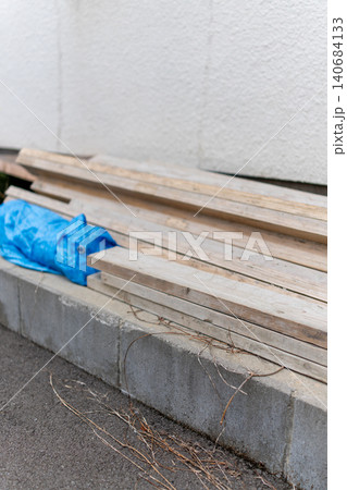 外壁沿いに置かれた廃材と雑草のある住宅まわり 外壁沿いに置かれた廃材と雑草のある住宅まわり 140684133