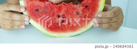 Boy Eating Watermelon Slice with Joy and Playful Expression 140684381