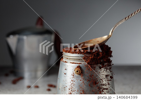 Grounded coffee is poured into a classic Italian aluminium moka pot. Grounded coffee is poured into a classic Italian aluminium moka pot. 140684399