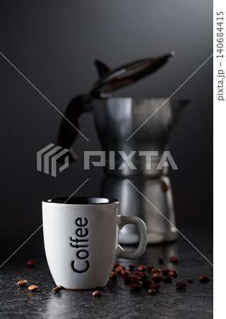 Cup of espresso and classic Italian aluminium moka pot on a black background. Cup of espresso and classic Italian aluminium moka pot on a black background. 140684415