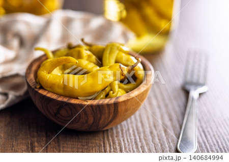 Pickled Yellow Banana Peppers In Wooden Bowl With Jar And Fork On Rustic Table Pickled Yellow Banana Peppers In Wooden Bowl With Jar And Fork On Rustic Table 140684994