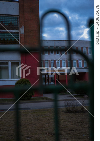Twilight view of Soviet era school in Minsk through fence bars 140685076