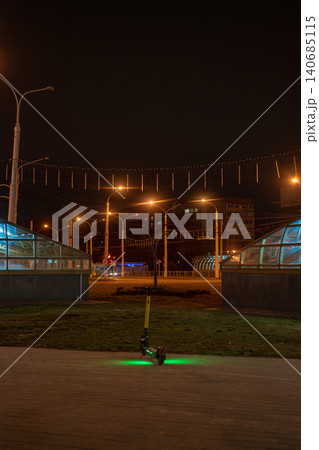 Minsk night e scooter on brick walkway by glass domed subway Minsk night e scooter on brick walkway by glass domed subway 140685115