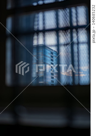 Wire mesh window view toward central Vilnius high rise at dusk Wire mesh window view toward central Vilnius high rise at dusk 140685232