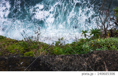 Atlantic surf pounds cliffside ledge and succulents in Madeira 140685306