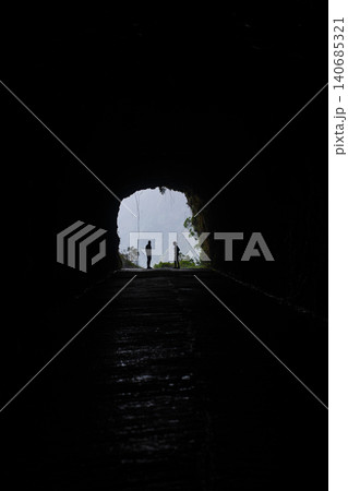 Hikers at tunnel mouth with misty cliffs and vines in Madeira, Hikers at tunnel mouth with misty cliffs and vines in Madeira, 140685321
