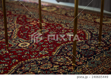 Ornate Persian style rug with brass table legs in Madeira interior Ornate Persian style rug with brass table legs in Madeira interior 140685449