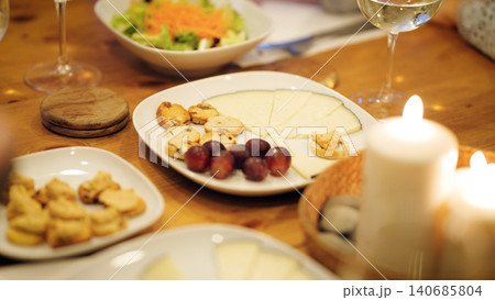 Friends enjoying cheese platter with wine and candles 140685804