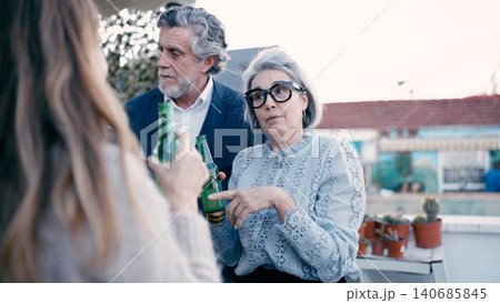 Seniors friends enjoying rooftop party talking and drinking beer Seniors friends enjoying rooftop party talking and drinking beer 140685845