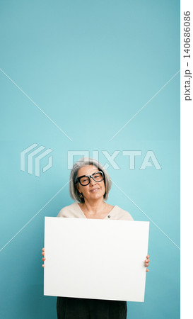 Senior woman holding blank white board banner Senior woman holding blank white board banner 140686086