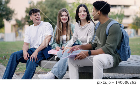 University students talking and studying on campus bench University students talking and studying on campus bench 140686262