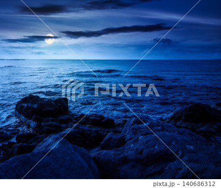 sea coast with stones and rocks at night. summer vacation background. full moon over seascape with rough terrain. fantasy relaxing at the sea. mysterious coast of bulgaria 140686312