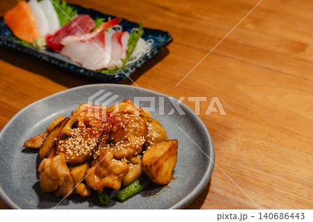 居酒屋のテーブルに並ぶ鶏肉とさつまいもの炒め物と刺身の盛り合わせ 140686443