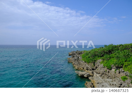 沖縄の岩場とターコイズブルーの海、緑の植生が広がる海岸風景 沖縄の岩場とターコイズブルーの海、緑の植生が広がる海岸風景 140687325