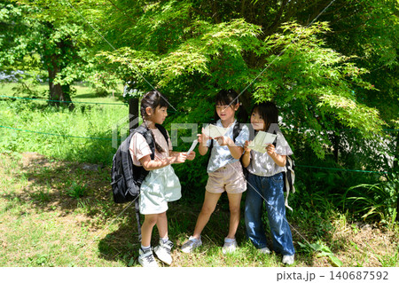 新緑の自然の中で地図を見てルートを発見し指差す女子小学生たち 新緑の自然の中で地図を見てルートを発見し指差す女子小学生たち 140687592