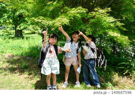 新緑の自然の中で地図を見てルートを発見し指差す女子小学生たち 新緑の自然の中で地図を見てルートを発見し指差す女子小学生たち 140687596