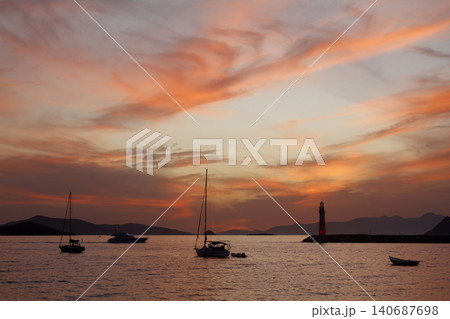 Seascape at sunshine. Lighthouse and sailings on the coast. Seaside town of Turgutreis and spectacular sunshine Seascape at sunshine. Lighthouse and sailings on the coast. Seaside town of Turgutreis and spectacular sunshine 140687698