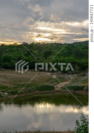 Peaceful forest lake reflecting dramatic sunset clouds above lush green woodland creating serene natural landscape tranquil atmosphere scenic beauty Peaceful forest lake reflecting dramatic sunset clouds above lush green woodland creating serene natural landscape tranquil atmosphere scenic beauty 140687721
