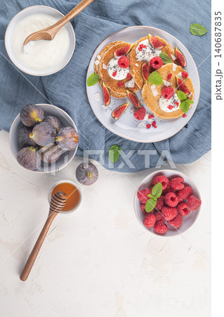 Pancakes with raspberries, figs, yogurt, coconut zest, honey and mint leaves on a plate. 140687835