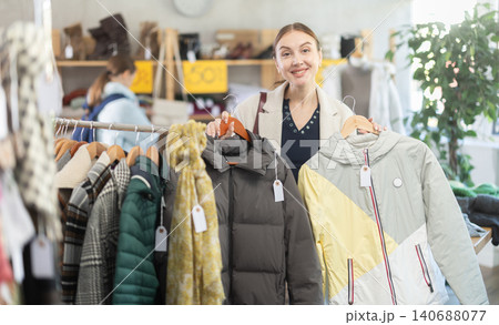 Adult woman chooses down jacket in clothing store 140688077