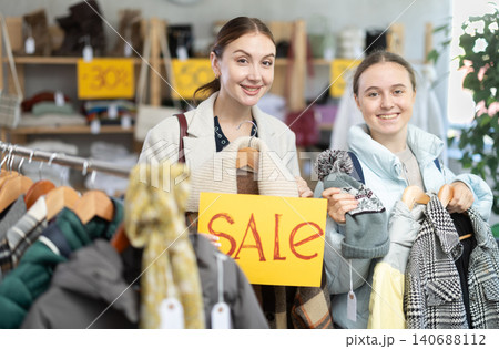 Happy mom and teenage daughter holding sale banner in clothing store 140688112