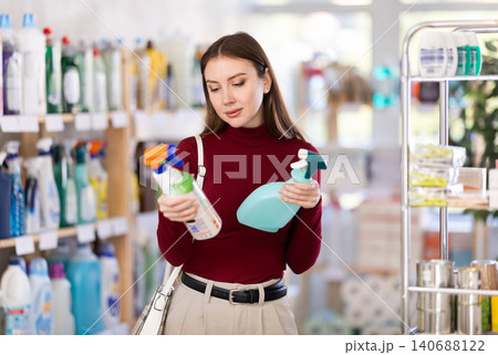 Young woman chooses cleaning spray in store 140688122