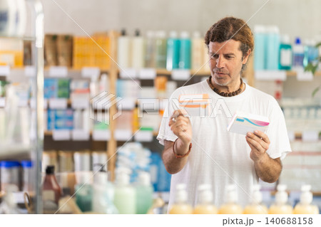 Adult man chooses pills at pharmacy Adult man chooses pills at pharmacy 140688158