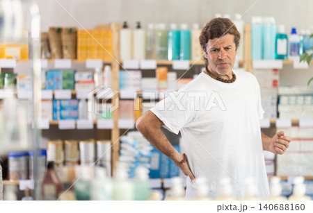 man holding his back in a pharmacy man holding his back in a pharmacy 140688160