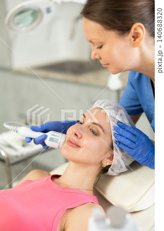 Adult woman cosmetologist doing whitening procedure to young woman Adult woman cosmetologist doing whitening procedure to young woman 140688320