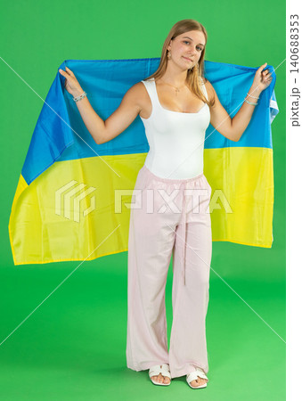Teenage girl holding Ukrainian flag in front of green screen 140688353
