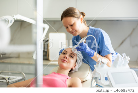 Adult woman cosmetologist doing whitening procedure to young woman 140688472