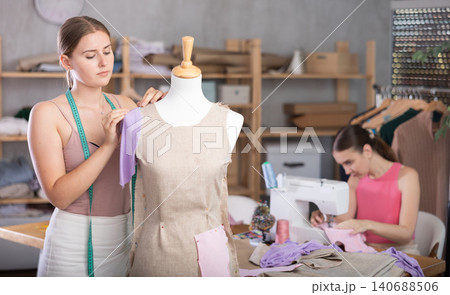 Adult woman sews female assistant working with mannequin 140688506