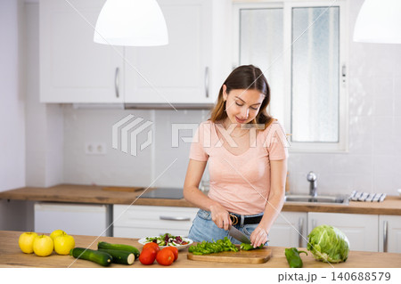 Portrait of woman cutting vegetable on kitchen Portrait of woman cutting vegetable on kitchen 140688579