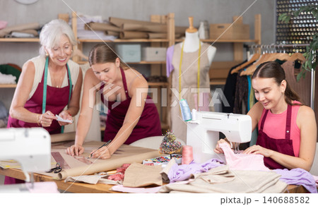 Dressmakers draw sketches of clothes and work on a sewing machine in the workshop 140688582