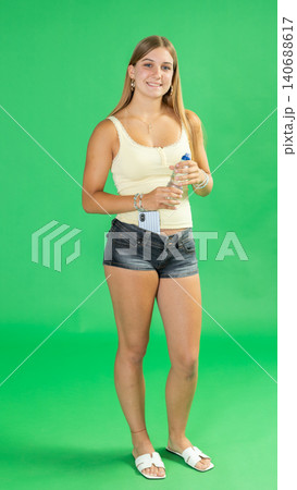 Teenage girl drinking water in front of green screen Teenage girl drinking water in front of green screen 140688617