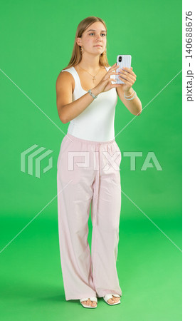 Teenage girl taking photo in front of green screen 140688676