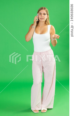 Teenage girl talking on mobile phone in front of green screen 140688686