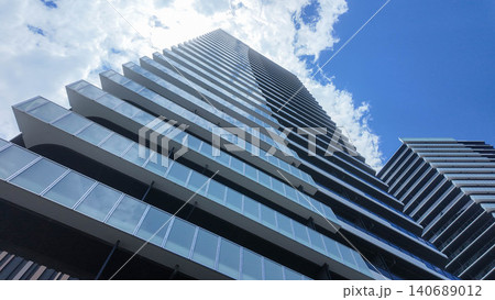 Low angle view of modern glass skyscraper architecture against blue sky. Low angle view of modern glass skyscraper architecture against blue sky. 140689012