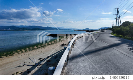 Scenic view of an empty coastal road with guardrail along the blue sea. Scenic view of an empty coastal road with guardrail along the blue sea. 140689015