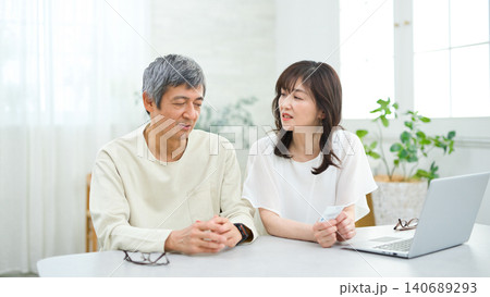 リビングでパソコンとカードを見る60代の夫婦 リビングでパソコンとカードを見る60代の夫婦 140689293