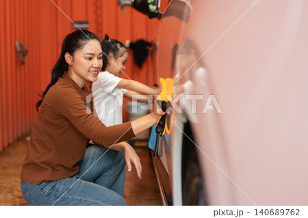 happy woman with child girl washing car with microfiber cloth in a self-service car wash station happy woman with child girl washing car with microfiber cloth in a self-service car wash station 140689762
