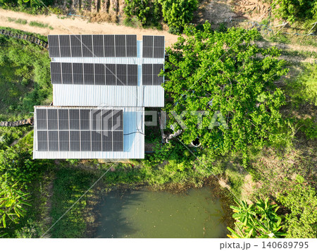 Rooftop solar panel installation on a rural farm building. Renewable energy generation, sustainable living and climate conscious infrastructure. Clean electricity production. Energy independence. Rooftop solar panel installation on a rural farm building. Renewable energy generation, sustainable living and climate conscious infrastructure. Clean electricity production. Energy independence. 140689795