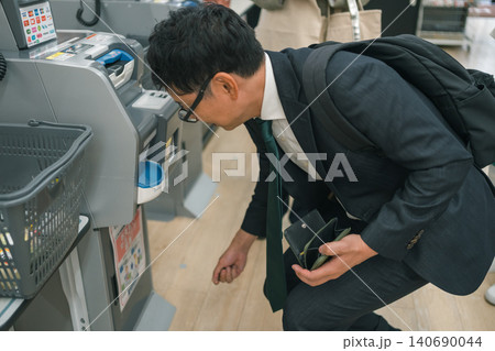 セルフレジでお金を落として拾うサラリーマン セルフレジでお金を落として拾うサラリーマン 140690044