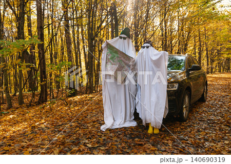 Two People in Halloween Ghost Costumes Walking Through Autumn Forest Two People in Halloween Ghost Costumes Walking Through Autumn Forest 140690319