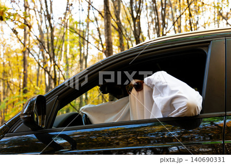 Person wearing ghost costume driving car while holding paper map, searching for direction and navigating route Person wearing ghost costume driving car while holding paper map, searching for direction and navigating route 140690331