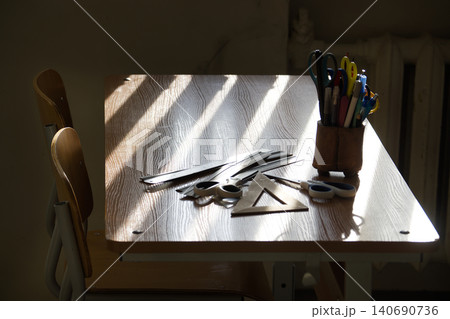 A sunlit school desk with various stationery and tools for learning. A sunlit school desk with various stationery and tools for learning. 140690736