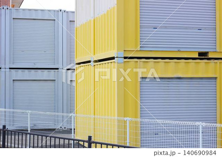 屋外敷地に2段に積み重ねられた黄色いシャッター付きレンタル収納コンテナ 屋外敷地に2段に積み重ねられた黄色いシャッター付きレンタル収納コンテナ 140690984